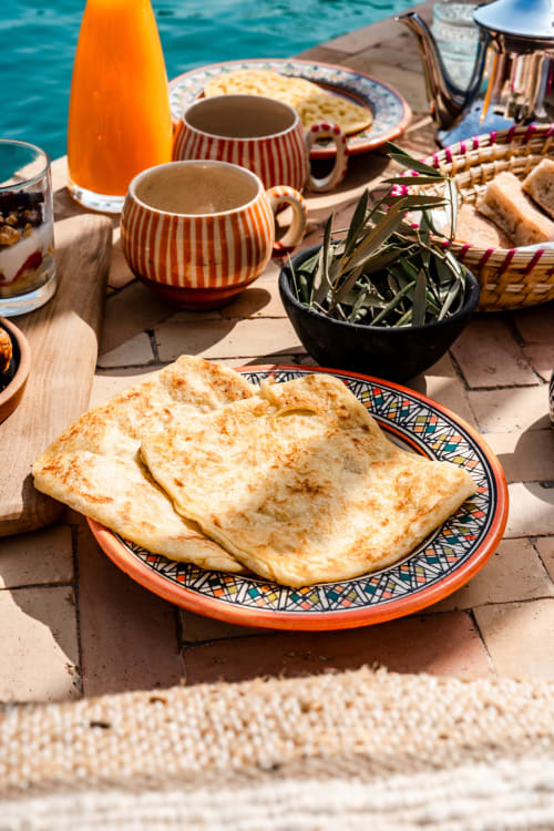 Petit-déjeuner marocain au Riad Arkaya à Essaouira : crêpes, café, jus d'orange frais et herbes aromatiques