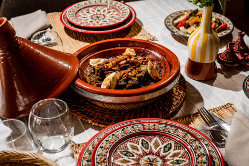 Plat de tajine marocain traditionnel servi au Riad Arkaya à Essaouira avec assiettes décoratives et mise de table.
