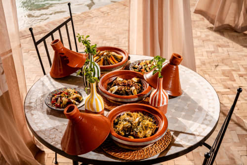 Tajines et poterie décoratives exposés sur une table ronde au Riad Arkaya à Essaouira, Maroc