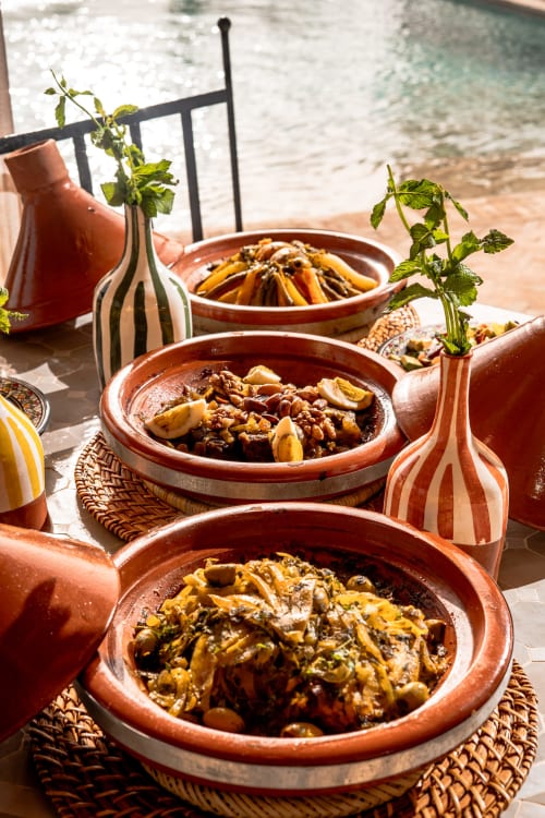 Plats de tajine marocains traditionnels servis au Riad Arkaya à Essaouira avec vue sur l'océan
