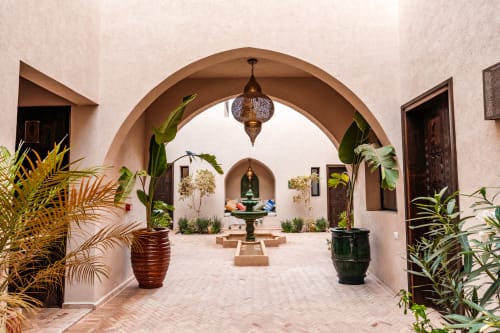 Cour du Riad Arkaya à Essaouira avec arcades, lanternes ornementales, plantes en pot et architecture traditionnelle marocaine