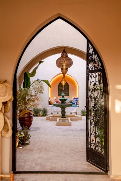 Porche marocain orné du Riad Arkaya à Essaouira avec portes en métal ouvragé, fontaine de cour et décor traditionnel