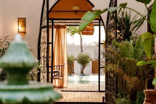 Entrée du Riad Arkaya à Essaouira avec portes noires ornementales, oliviers, vue sur la piscine et patio marocain