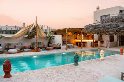 Piscine du Riad Arkaya au coucher de soleil à Essaouira avec eau turquoise, transats et architecture marocaine