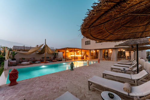 Piscine et patio de luxe du Riad Arkaya au crépuscule à Essaouira avec transats et bâtiment principal illuminé