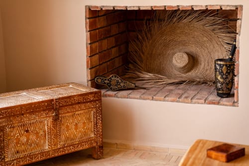 Foyer du Riad Arkaya à Essaouira orné d'un coffre en bois sculpté, d'un panier tissé et d'ornements marocains