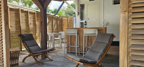 Covered patio at Habitation Villa Les Cassias bungalow with lounge chairs, bar seating, and wooden shutters in Petit Bourg,