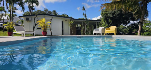 Kristallklares Swimmingpool der Habitation Villa Les Cassias in Guadeloupe mit weißem Cottage und tropischen Palmen