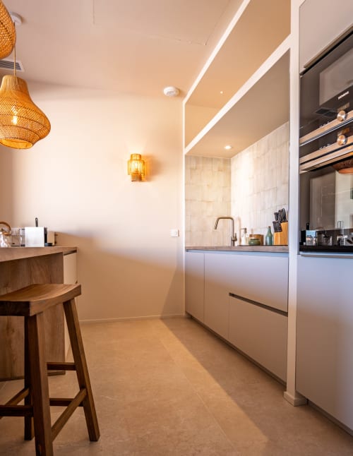 Cuisine moderne de la villa Can Jeannette à Collioure avec bar en bois, armoires blanches et éclairage chaleureux