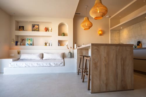 Chambre de villa moderne à Can Jeannette à Collioure avec lit blanc, luminaires suspendus tressés, comptoir en bois et aménagements intégrés