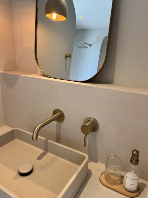 Salle de bain moderne avec miroir rond, robinetterie en laiton et pommeau de douche pluie à la villa Can Jeannette à Collioure