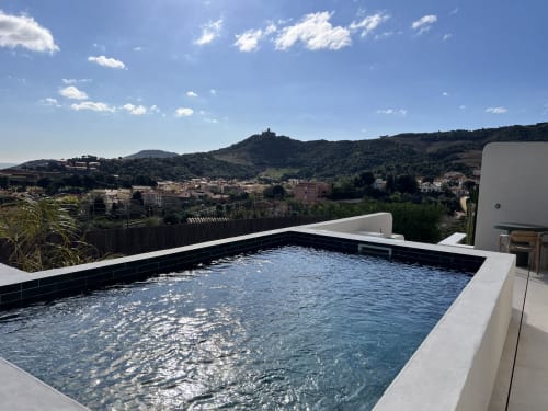 Piscine de villa moderne surplombant la ville de Collioure avec les collines méditerranéennes et ciel dégagé à l'hôtel-boutique Can Jeannette