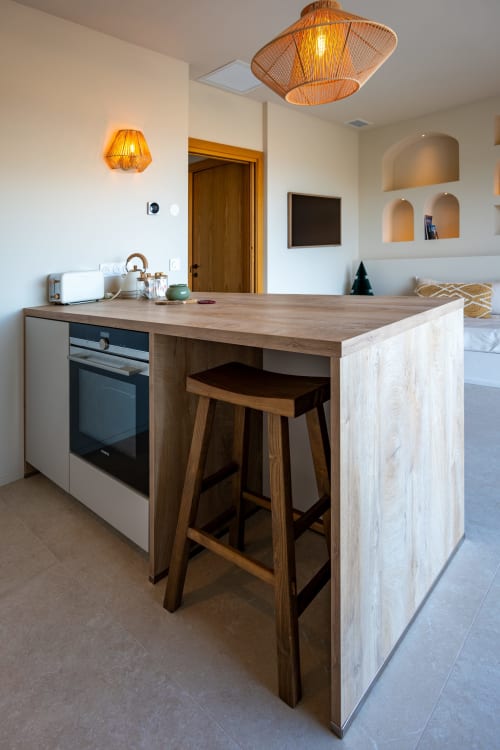 Îlot de cuisine moderne avec bar en bois à la villa Can Jeannette à Collioure, éclairage suspendu et vue sur mer