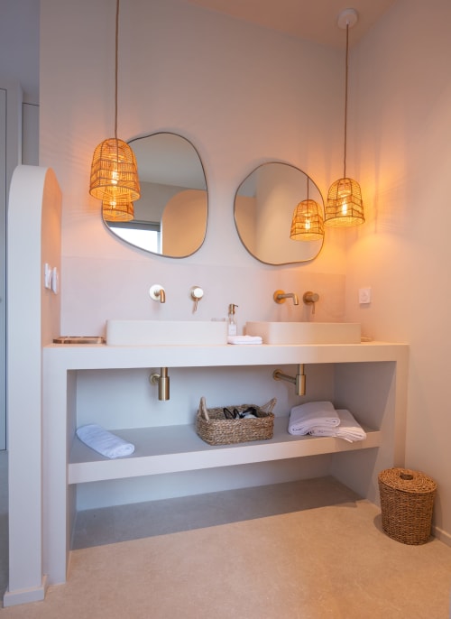 Salle de bain moderne de la villa Can Jeannette à Collioure avec vasques doubles, suspensions en osier et étagères ouvertes