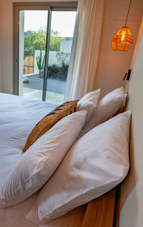 Chambre luxueuse de la villa Can Jeannette à Collioure avec vue mer, oreillers blancs et lampe suspendue