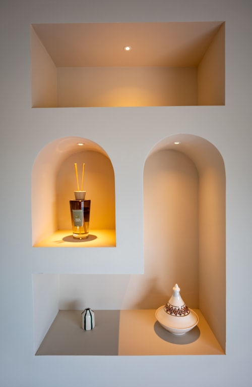 Niche moderne aux éclairages ambrés avec flacon de parfum et ornements décoratifs à la villa Can Jeannette