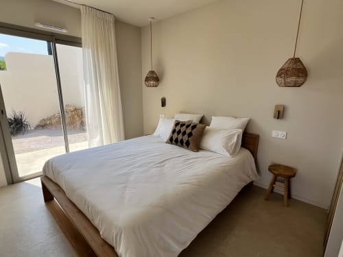 Chambre moderne aux draps blancs à la villa Can Jeannette à Collioure, avec luminaires en suspension tressés et terrasse avec vue sur mer