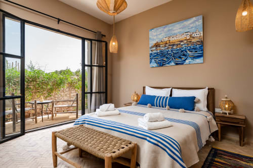 Chambre Mogador au Riad Arkaya, Essaouira : chambre bleu et blanc avec lit queen-size, terrasse vue jardin et œuvres côtières.