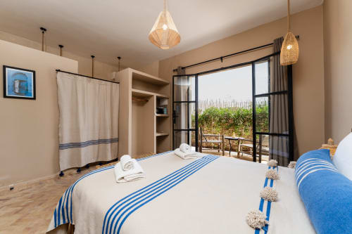 Chambre Mogador au Riad Arkaya, Essaouira : chambre lumineuse avec lit queen-size, touches bleues, luminaires suspendus tissés et jardin