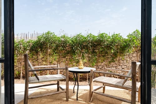 Terrasse privée du Riad Arkaya à Essaouira avec mobilier en bois, table et vue sur le jardin luxuriant et les murs en pierre