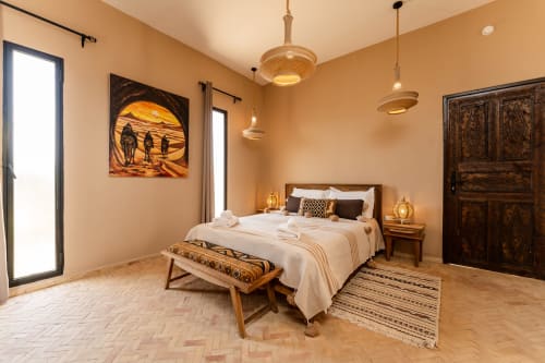 Chambre chaleureuse aux tons terreux au Riad Arkaya à Essaouira avec lit queen, décor marocain, luminaires suspendus et vue sur le jardin