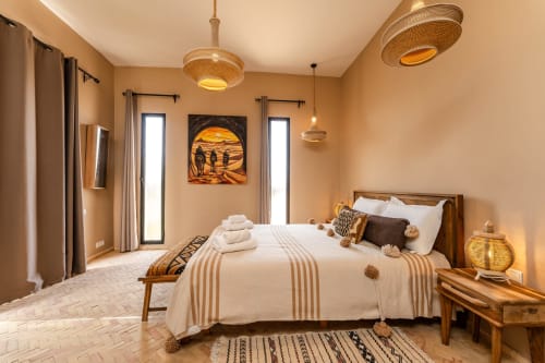 Chambre Beldi du Riad Arkaya à Essaouira avec vue sur le jardin, décor beige, lit en bois et art marocain