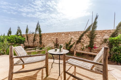 Terrasse-jardin du Riad Arkaya avec chaises en bois, mur en pierre et cactus à Essaouira