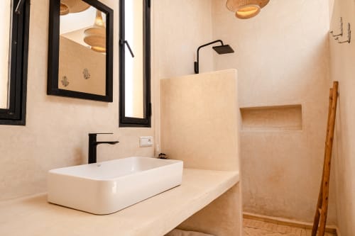 Salle de bain moderne du Riad Arkaya à Essaouira avec vasque blanche, robinetterie noire et douche à l'italienne