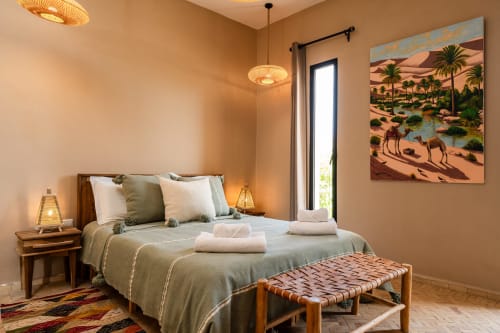 Chambre chaleureuse et élégamment décorée au Riad Arkaya à Essaouira avec lit queen-size, œuvres d'art du désert et vue sur le jardin
