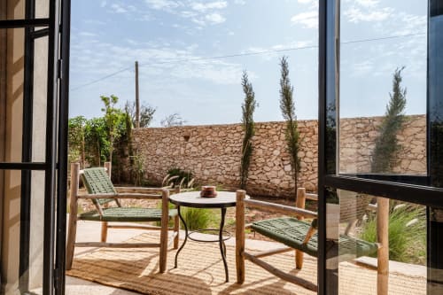 Terrasse privée avec vue sur le jardin du Riad Arkaya à Essaouira, avec chaises longues et table donnant sur un mur en pierre