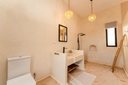 Salle de bains accessible au Riad Arkaya avec équipements modernes, éclairage suspendu et porte-serviettes en bois à Essaouira