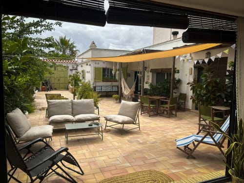 Patio de Cala Pipa con zona de descanso, toldo amarillo y plantas en macetas en Poble Nou del Delta, Tarragona