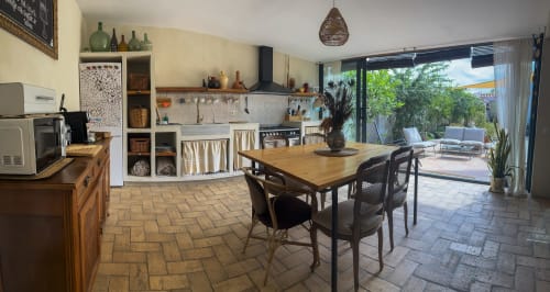 Moderna zona de cocina-comedor del hotel Cala Pipa en Poble Nou del Delta con mesa de madera y vistas a la terraza abierta