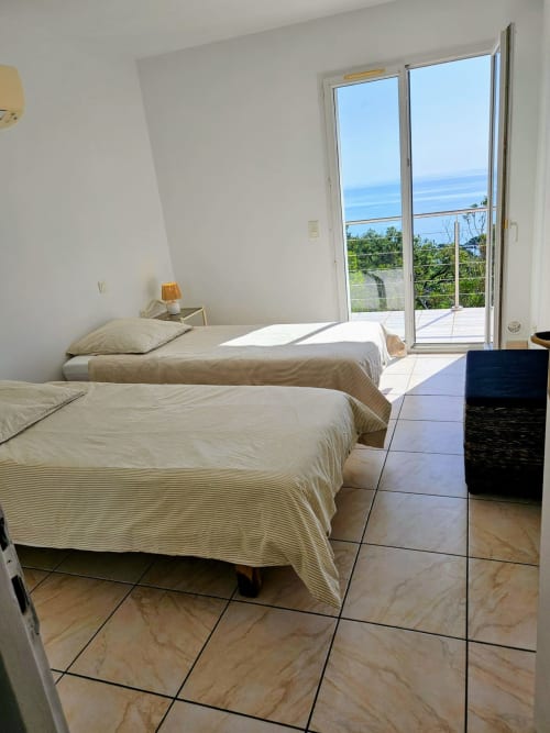 Bright twin bedroom with sea view in Villa Eva at Corsu Di Core, Favone, featuring modern furnishings and balcony access