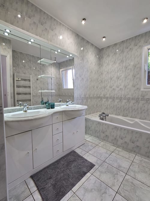 Modern bathroom in Villa Eva at Corsu Di Core, Favone, with dual marble sinks, rainfall shower, and heated pool access