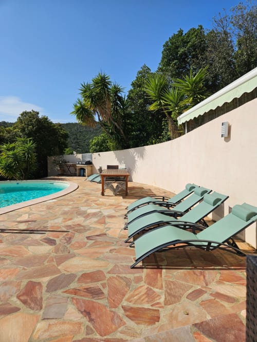Villa Eva pool area with turquoise loungers, heated pool, white walls, and lush gardens at Corsu Di Core, Favone