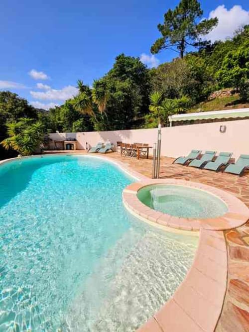 Heated swimming pool and hot tub at Corsu Di Core villa in Favone with lounge chairs and tropical garden views