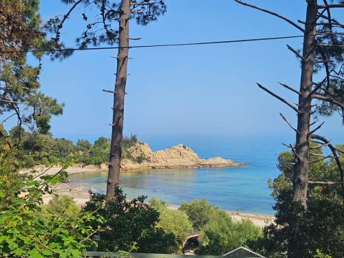 Scenic coastal view from Villa Eva at Corsu Di Core, Favone: turquoise bay with sandy beach, rocky peninsula, and