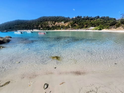 Turquoise beach at Favone with white sand, moored boats, and forested hillside, Villa Eva sea view