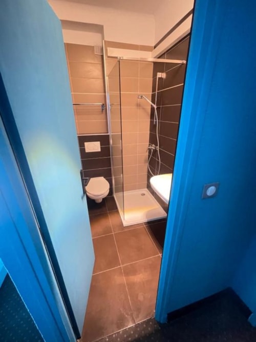 Salle de bains moderne de la Chambre deluxe à l'Hôtel New Fregate, Canet-en-Roussillon, avec douche, toilettes et carrelage marron
