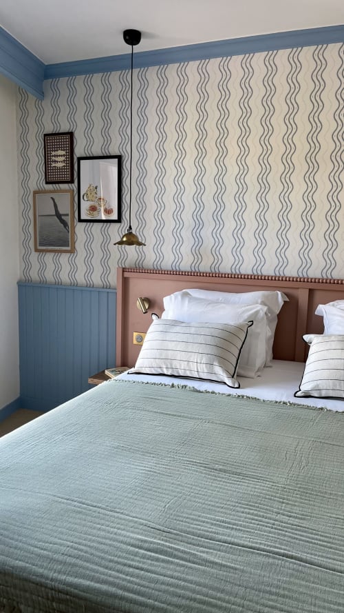 Chambre double de l'hôtel Saint Enogat à Dinard avec papier peint motifs ondulés, lambris bleus et lustre en laiton