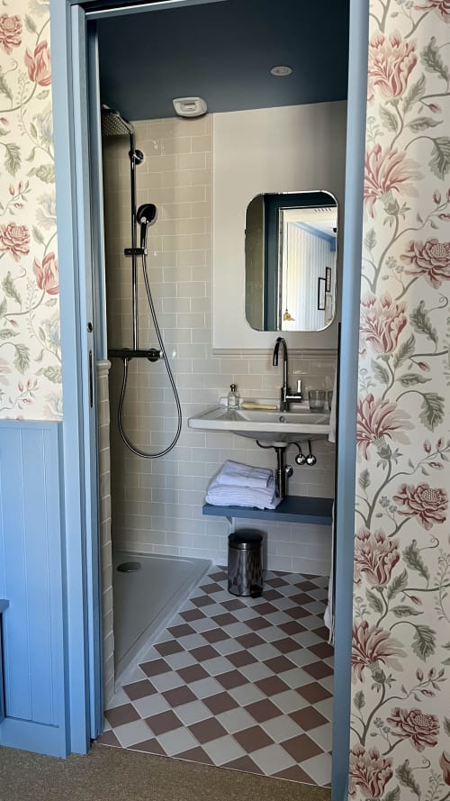 Salle de bains moderne dans une chambre double standard de l'Hôtel Saint Enogat à Dinard, équipée d'une douche, d'un lavabo et d'un carrelage à damier