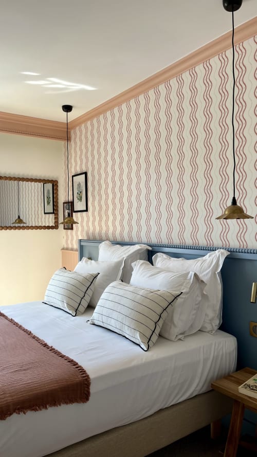 Chambre de l'Hôtel Saint Enogat avec papier peint rayé, tête de lit bleue, literie blanche et luminaires suspendus en laiton