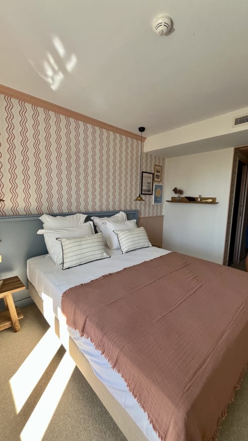 Chambre double moderne de l'Hôtel Saint Enogat à Dinard avec tête de lit rayée, oreillers blancs et plaid terracotta