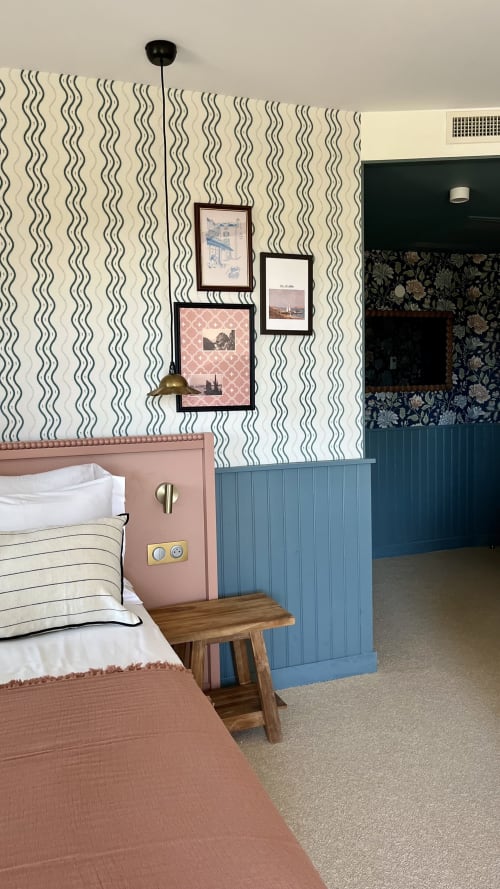 Chambre triple de l'Hôtel Saint Enogat à Dinard avec lit rose, papier peint ondulé, lambris bleu et œuvres d'art encadrées
