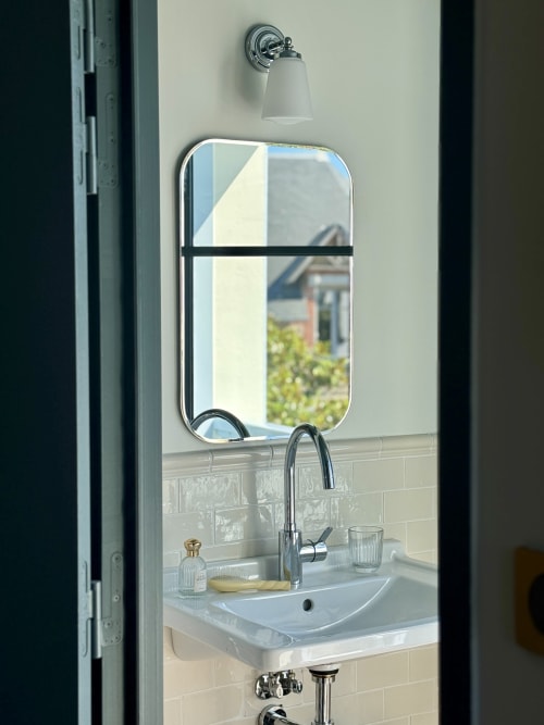 Salle de bains de l'Hôtel Saint Enogat avec lavabo moderne, miroir, robinetterie chromée et applique murale à Dinard