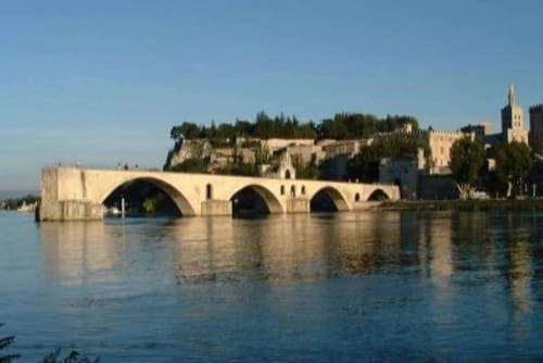 Pont de pierre historique enjambant le Rhône à Avignon avec palais médiéval et clocher
