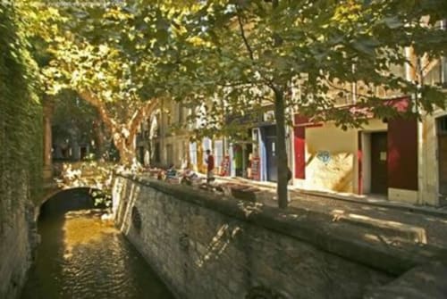 Charmante rue pavée avec canal et bâtiments colorés à l'hôtel Oriflamme & Travertin en France