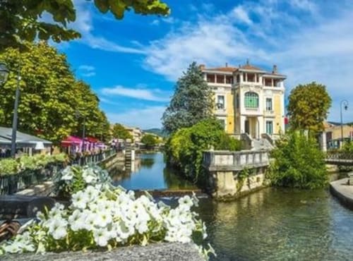 Hôtel Oriflamme & Travertin en France avec manoir jaune, canal, fleurs blanches et paysage verdoyant