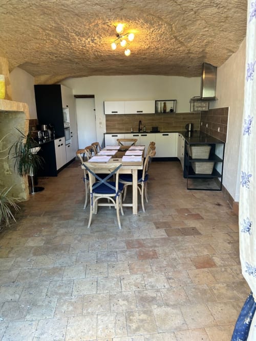 Cuisine-salle à manger Maison Melrose avec plafond en pierre rustique, table en bois et mobilier crème à Vouvray